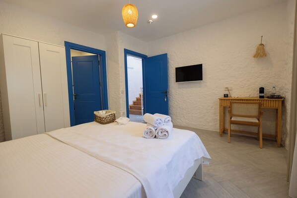 A bedroom with a bed, a desk, a chair, and a TV on the wall. - REF Alacati (Cesme)