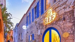 A narrow cobblestone street with stone buildings, a blue door, and a sign that reads 'REF'. - REF Alacati (Cesme)