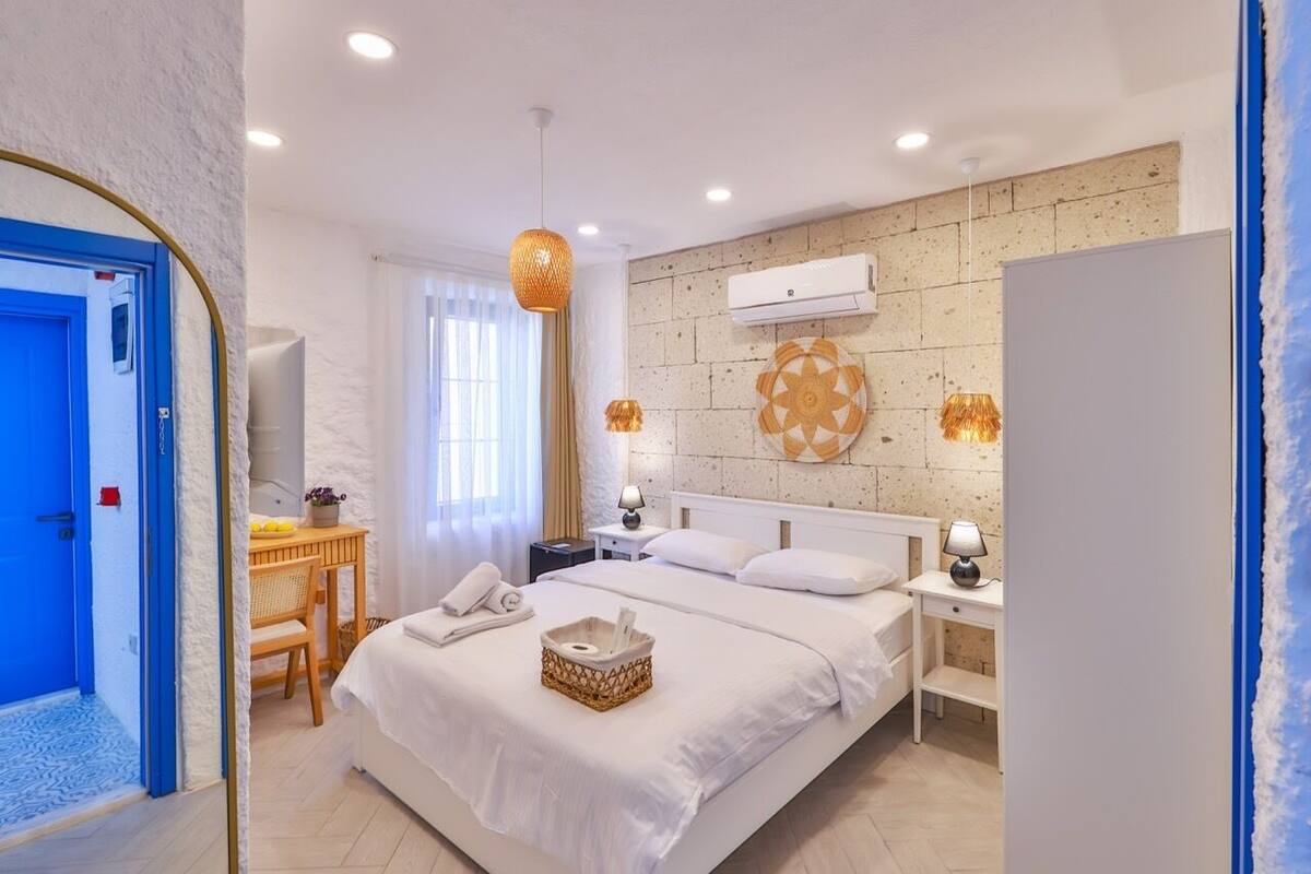 Ein modernes Hotelzimmer mit einem großen Bett, Nachttischen, einem Schreibtisch und einem Kleiderschrank.