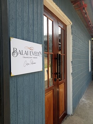 Segnale per Balai Evelyn Transient Home, con una porta in legno e rivestimento blu.