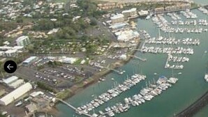 Vista aérea de un puerto deportivo con numerosas embarcaciones amarradas, rodeado de edificios y vegetación.