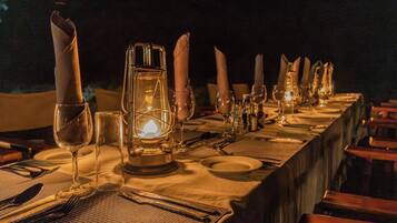 A long dining table set for a meal with candles, a lantern, and a warm ambiance.