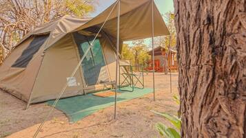 Uma tenda com um toldo, um tapete verde e uma cadeira.