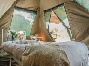 A tent with a bed, a small table, and a chair. - Khwai Mokoro Safaris and Campsites (Khwai)