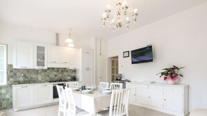 A modern kitchen with white cabinetry, a dining table set for four, and a chandelier.