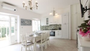 A spacious kitchen with white cabinetry, a dining table set for four, and a chandelier.
