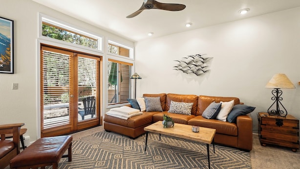A living room with a brown leather sofa, a wooden coffee table, and a patterned rug.