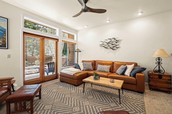 A living room with a brown leather sofa, a wooden coffee table, and a patterned rug.
