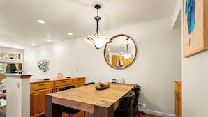 A modern kitchen with a wooden dining table, black chairs, and a round mirror on the wall.