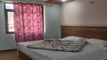 A bedroom with a bed, a window with curtains, and a headboard.