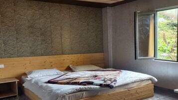 Un dormitorio moderno con estructura de cama de madera, cabecera y un ventanal que ofrece vistas al verde exterior.