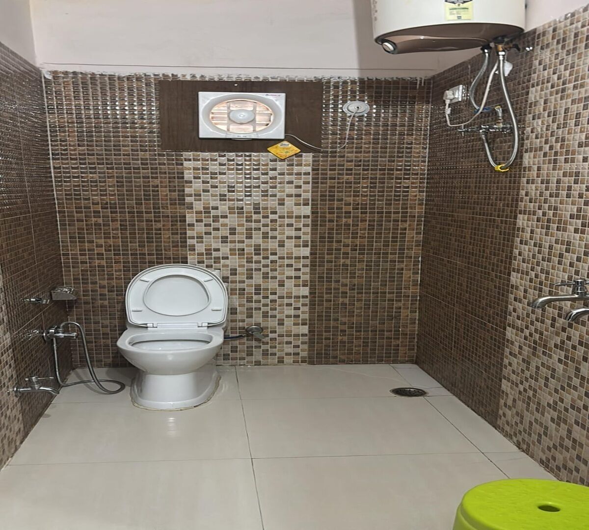 A bathroom with a toilet, a shower, and a tiled wall.