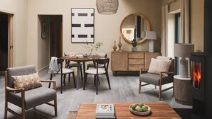 A cozy living room with a dining area, a fireplace, and a large mirror.