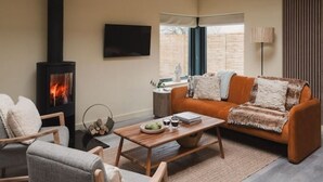 A cozy living room with a fireplace, a sofa, a coffee table, and a TV mounted on the wall.