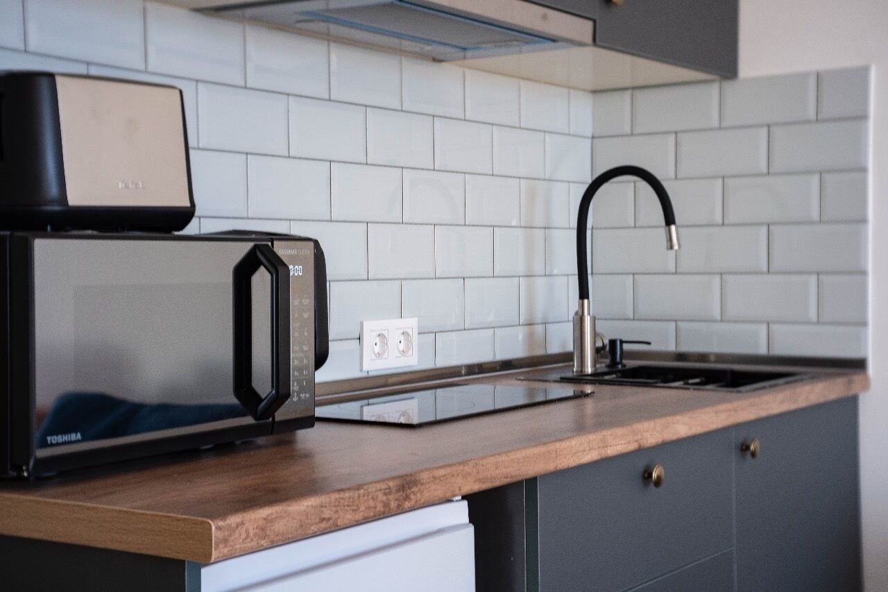 Una cocina con microondas, tostadora, fregadero y encimera de madera.