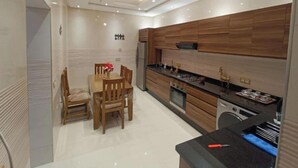 A modern kitchen with wooden cabinets, a dining table with chairs, and a built-in oven. - Chez bousfyha (Marrakech)