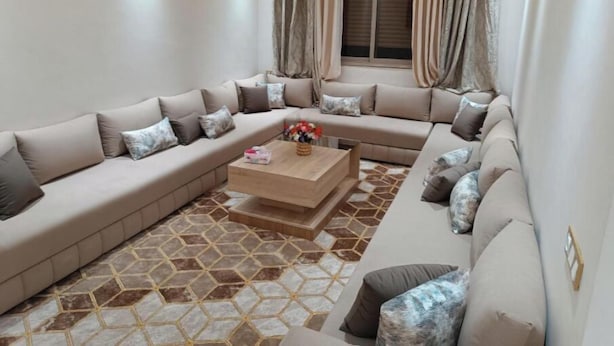 A living room with a sectional sofa, a coffee table, and a patterned floor. - Chez bousfyha (Marrakech)