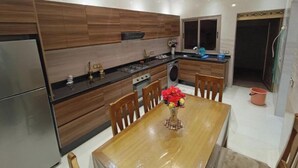 A modern kitchen with wooden cabinetry, stainless steel appliances, and a dining area with a table and chairs. - Chez bousfyha (Marrakech)
