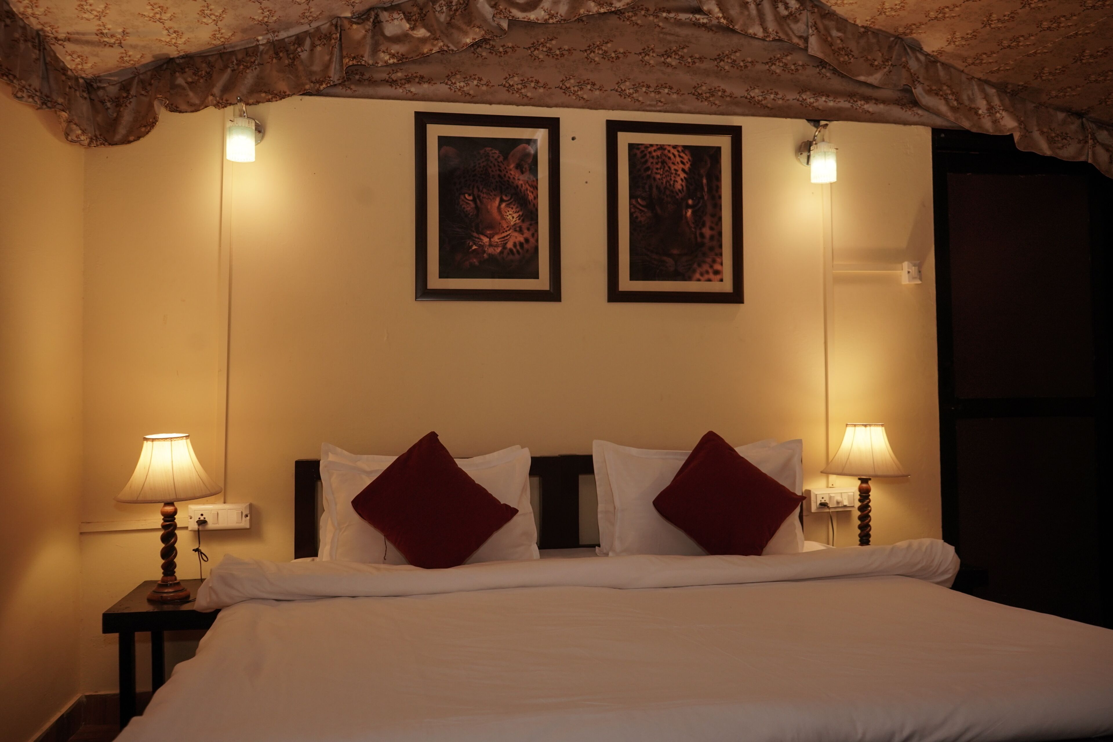 A hotel room with a bed, two wall-mounted lamps, and two framed pictures above the bed.