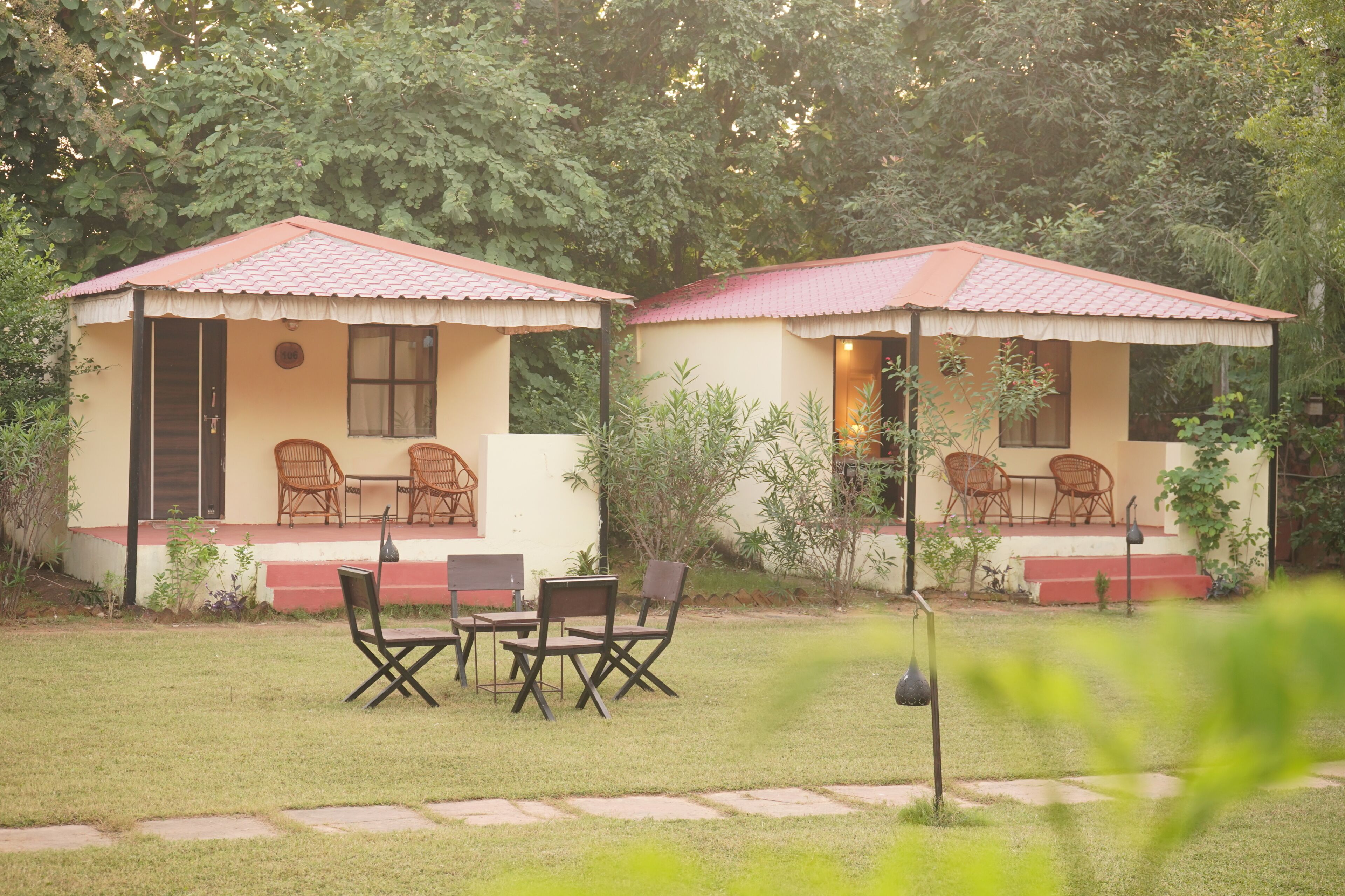 Two small, single-story buildings with red-tiled roofs and a patio area with chairs and a table.