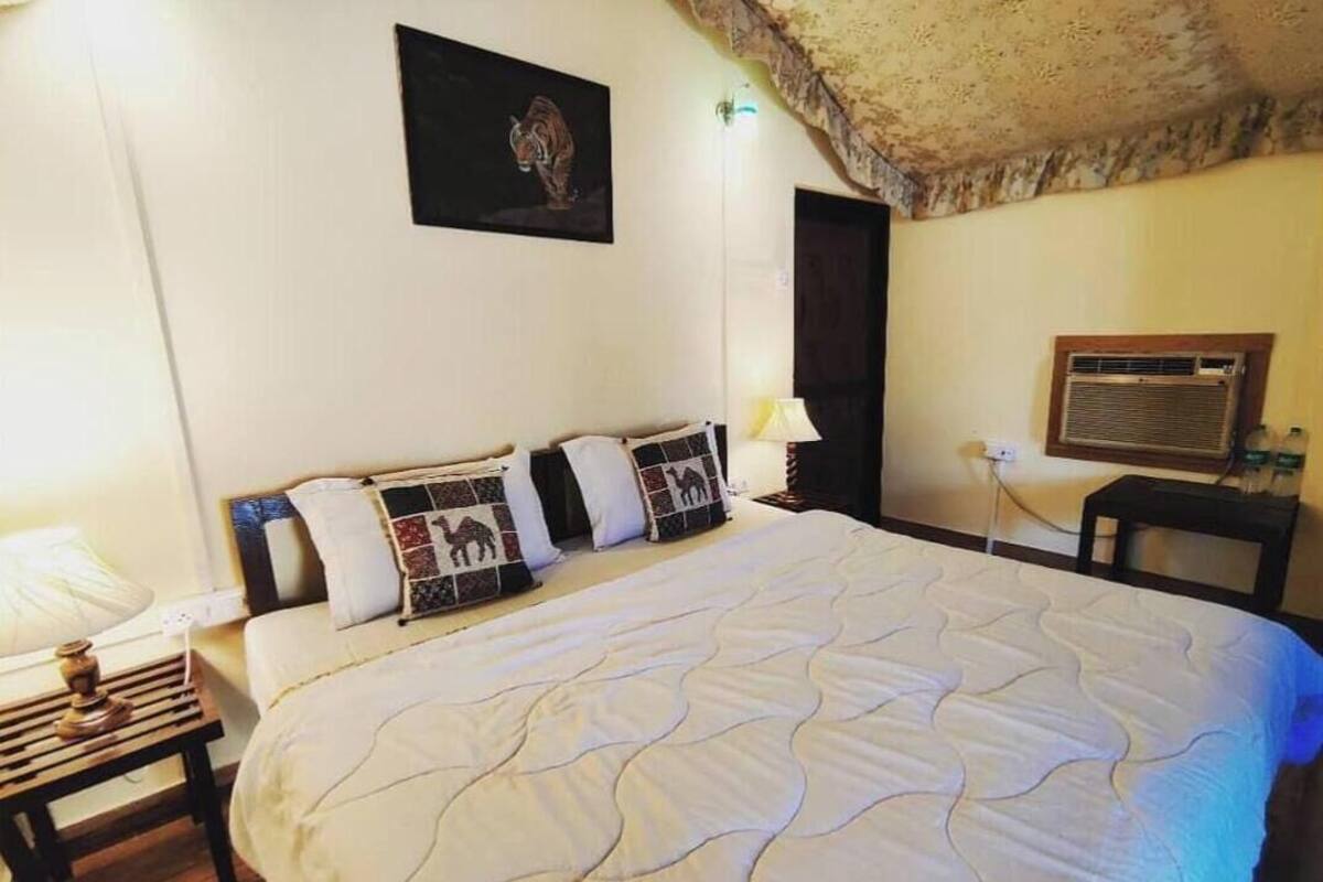 Ein Schlafzimmer mit einem großen Bett, einem Nachttisch, einer Lampe, einer Wandklimaanlage und einem gerahmten Bild.