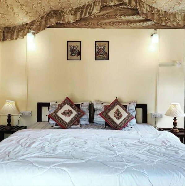 Une chambre d’hôtel avec un lit, deux tableaux représentant des tigres encadrés au mur et deux coussins décoratifs.