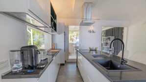 A modern kitchen with white cabinetry, a stainless steel sink, and a coffee machine. - Dream Sardinia: Villa la Gioia, luxury with sea views and unique sunsets (Quartu Sant'Elena)