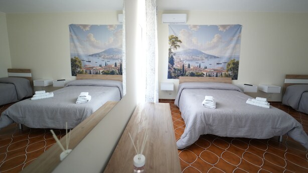 A hotel room with two beds, a wooden table, and a large window.
