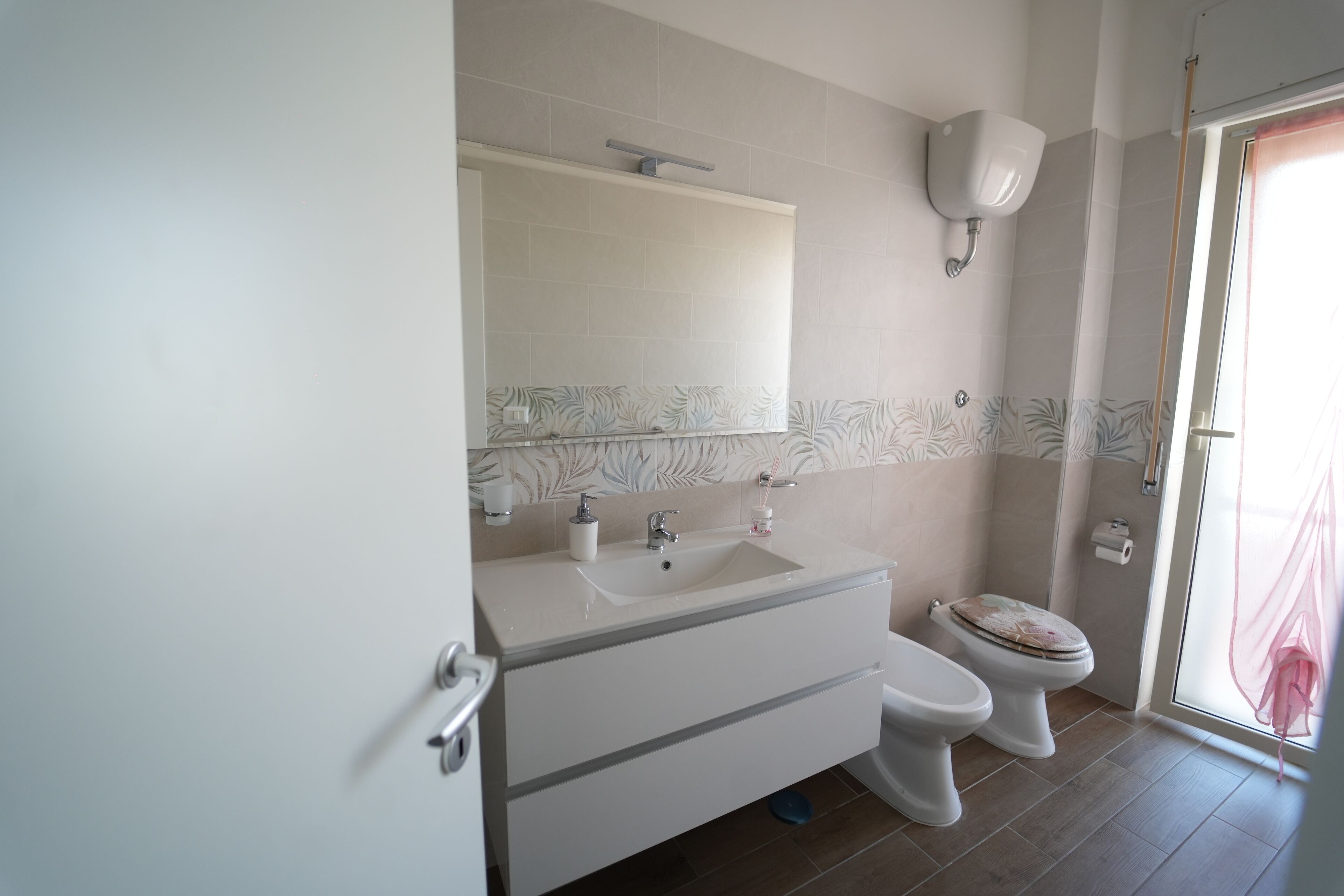 Et badeværelse med en hvid vask, toilet og bruseniche.