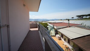 A balcony with a view of the sea and mountains.