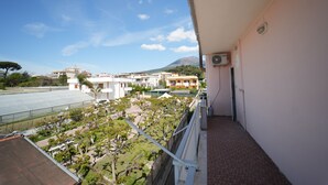 A balcony with a view of a sports field, buildings, and a mountain.