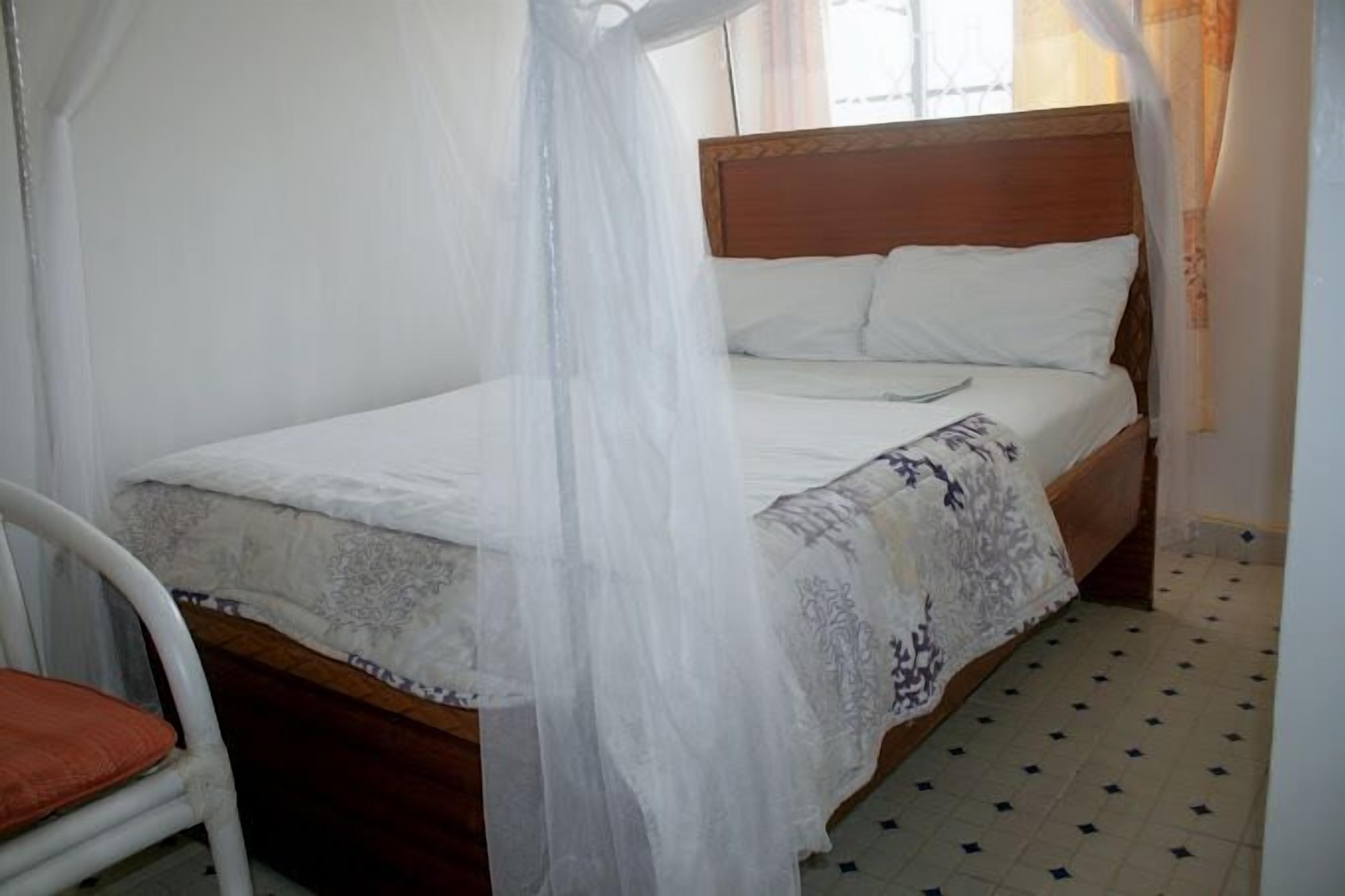 A bed with a wooden headboard, white bedding, and a canopy.