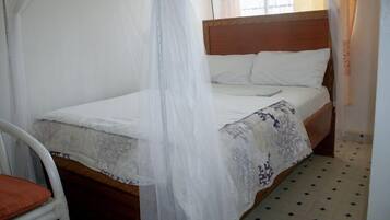 A bed with a wooden headboard, white bedding, and a canopy.