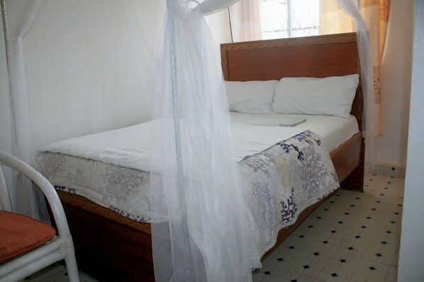 Una cama con cabecera de madera, ropa de cama blanca y dosel.