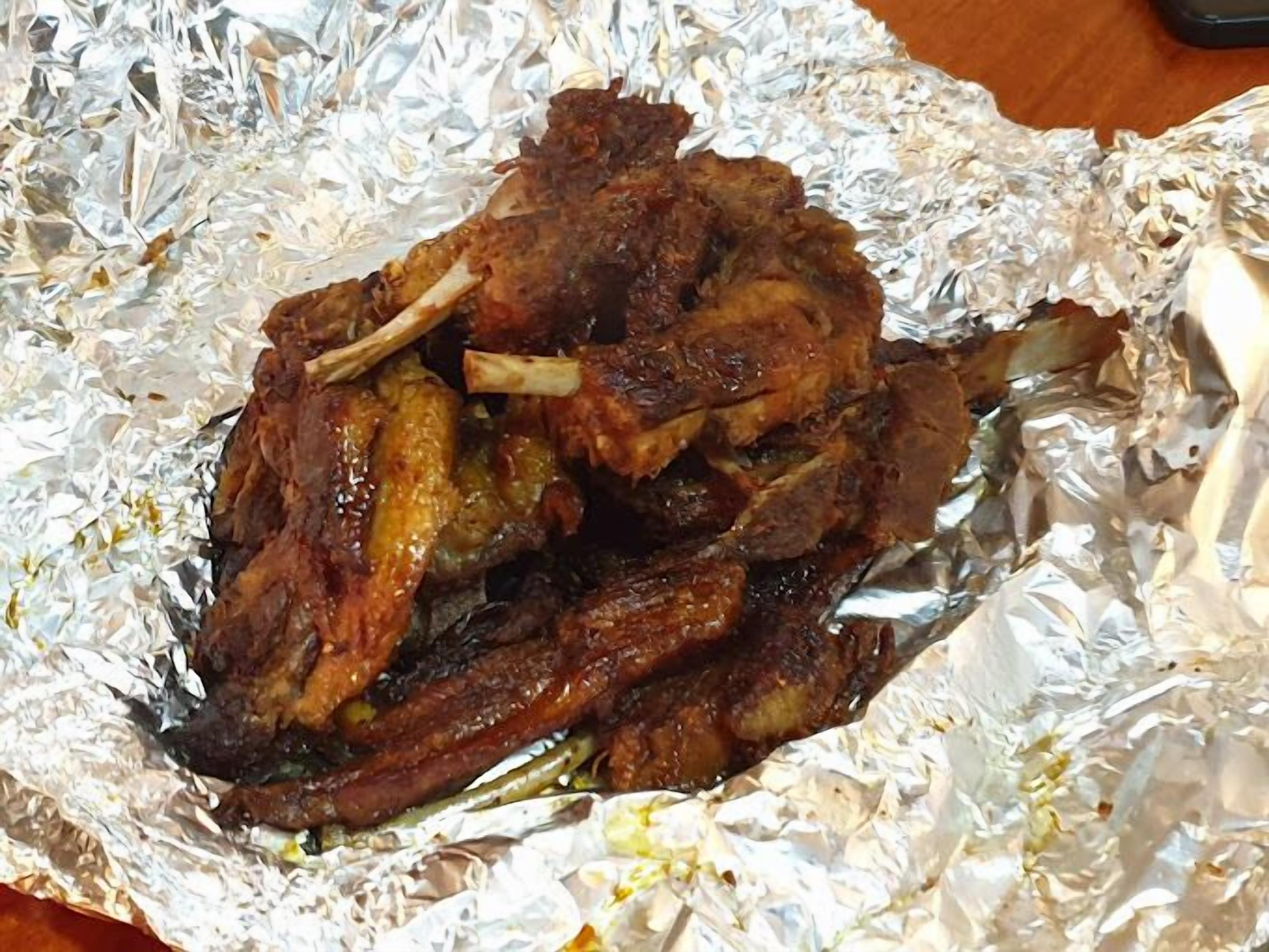 Un plat composé de viande grillée, servi sur du papier d’aluminium.