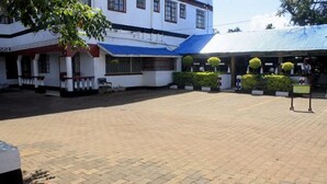 A building with a white exterior, blue roof, and a paved courtyard. - Siaya White Hotel (Siaya)