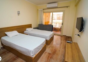 Une chambre d’hôtel avec deux lits simples, une télévision et un balcon avec vue.