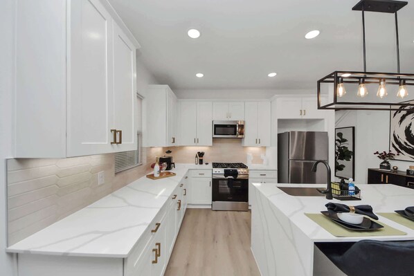 Enjoy cooking in this well-lit kitchen with a gas stove, microwave, and stainless steel refrigerator.