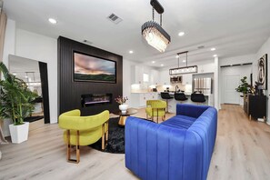Relax in this stylish living room with a large flat-screen TV, comfortable sofa, and cozy armchair.