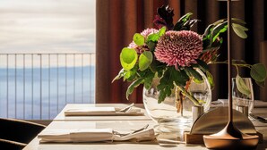 A table set for dining with a vase of flowers, a lamp, and a view of the sea. - Hochblauen Hotel (Schliengen)