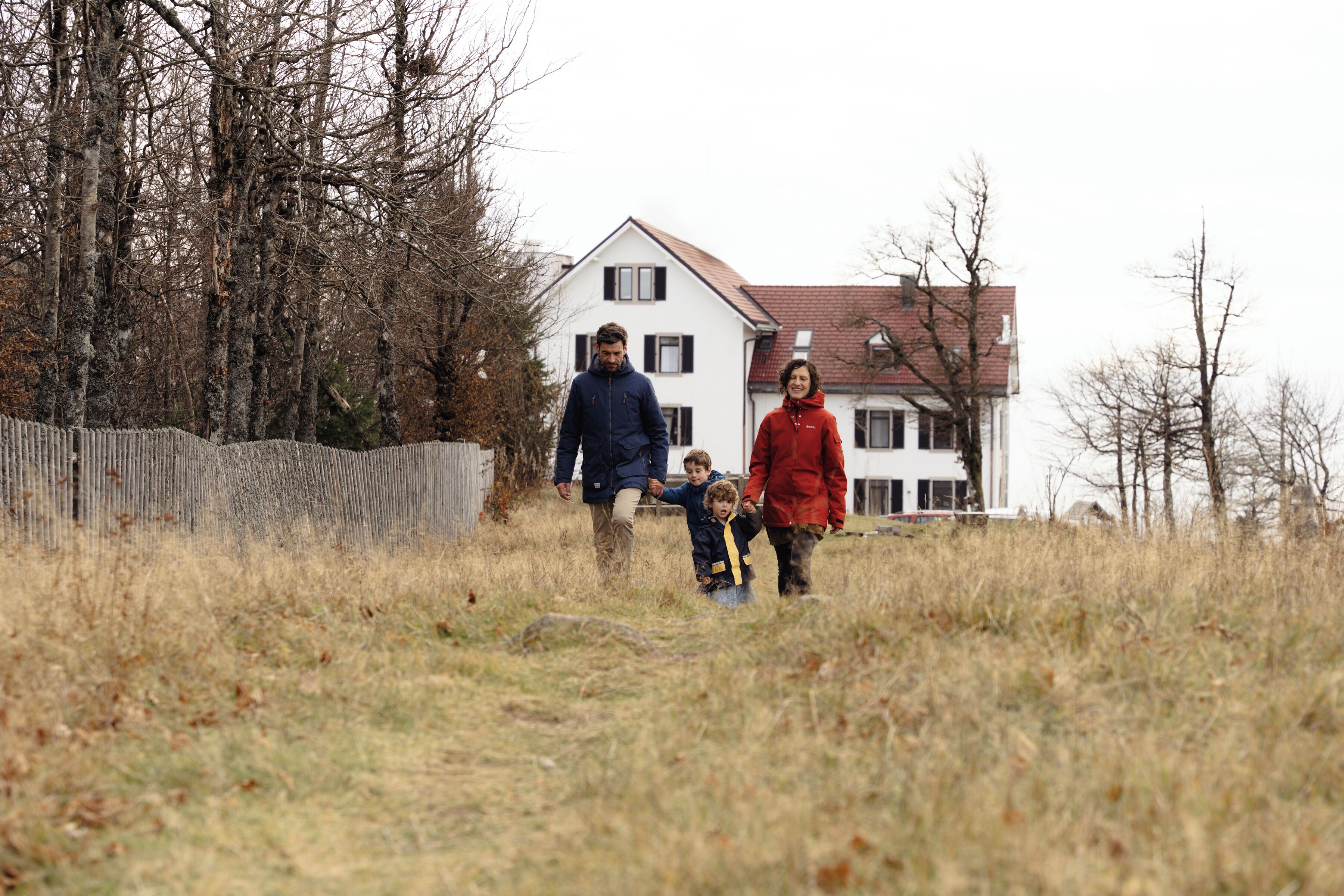 A family walking on a grassy path with a house in the background.