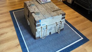Un salon chaleureux avec un canapé en cuir marron, une table basse en bois sur laquelle sont posés des magazines, une petite table blanche avec une lampe et une cheminée.