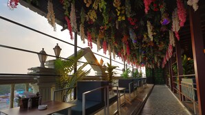 A balcony with seating, hanging floral decorations, and a patterned floor. - Balkrishna Palace (Jaypur)