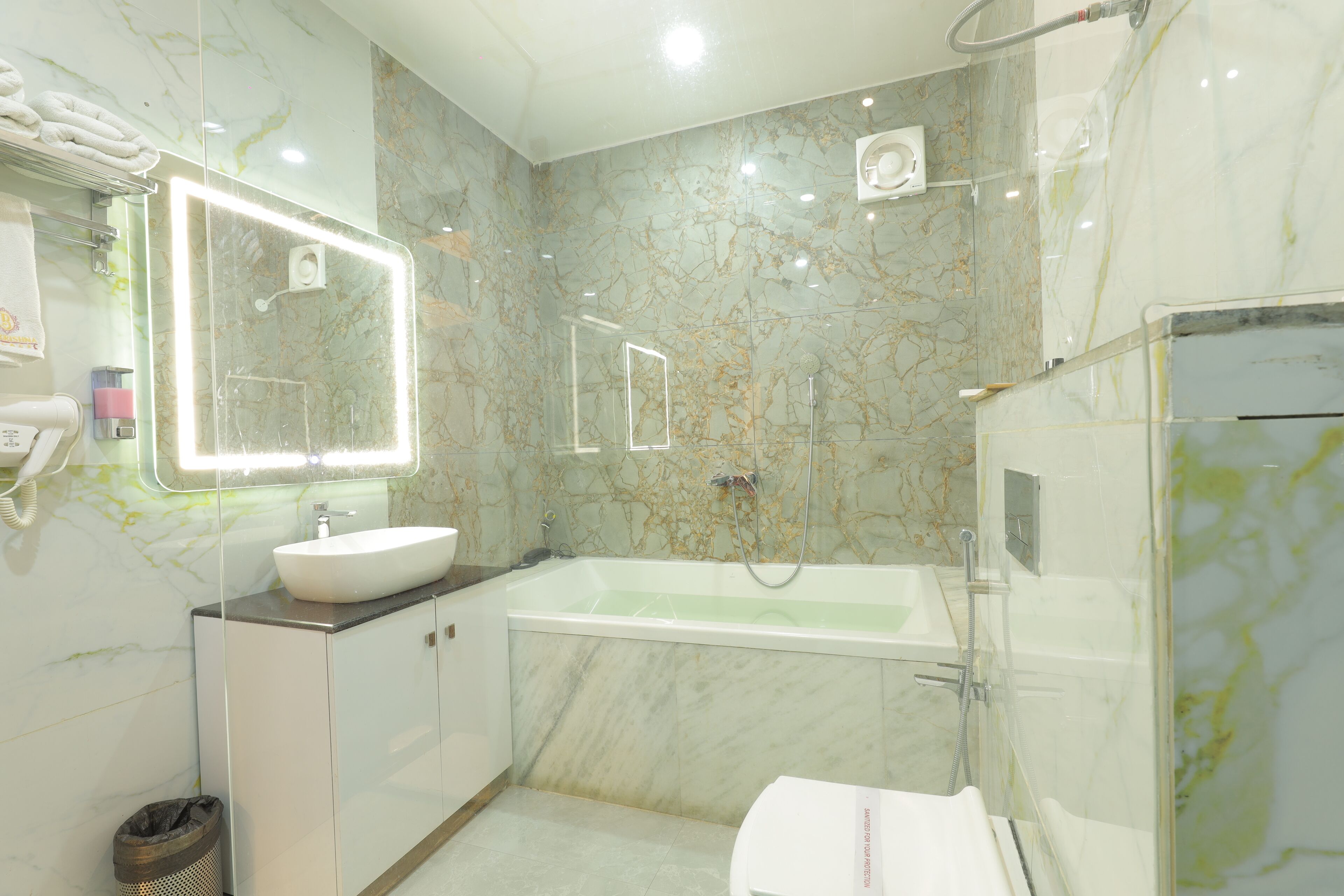 A bathroom with a marble wall, a sink, a bathtub, and a shower.