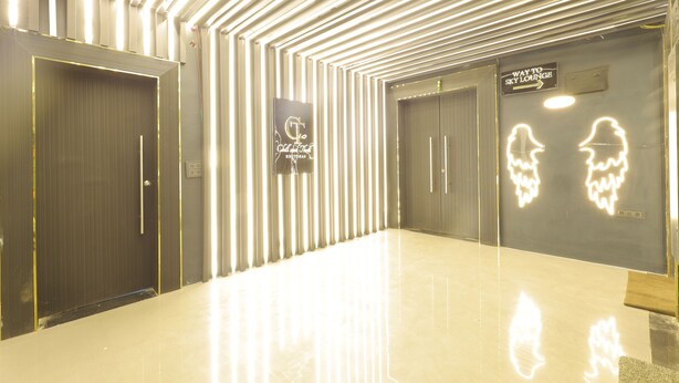A modern hotel lobby with a reflective floor, a reception desk, and directional signs to the Sky Lounge. - Balkrishna Palace (Jaypur)