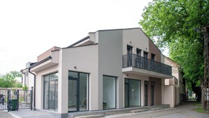 A modern two-story building with large windows and a balcony.