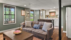 A living room with a sofa, coffee table, and a view of the kitchen.