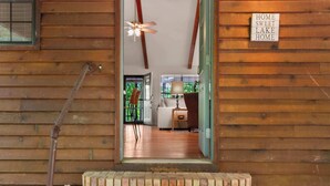A wooden cabin interior with a staircase leading to a living area, a ceiling fan, and a sign reading 'HOME SWEET LAKE HOME'.