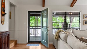 A room with a wooden floor, a blue door, a white couch, and a window with blinds.
