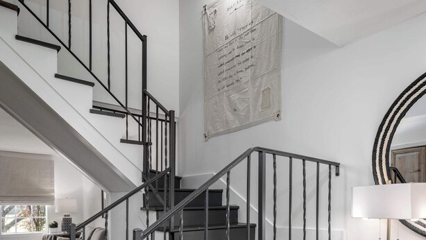 Una escalera moderna con barandales negros y paredes blancas.
